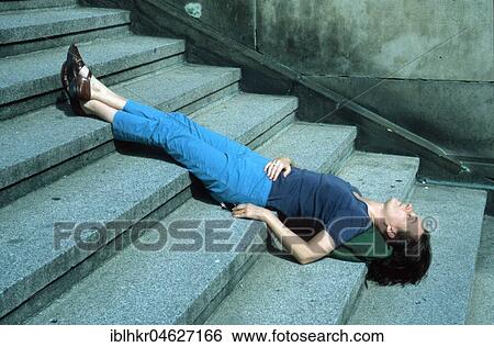 Stock Photograph - Woman sleeping with head down on stairs, Berlin, Germany, Europe. Fotosearch
