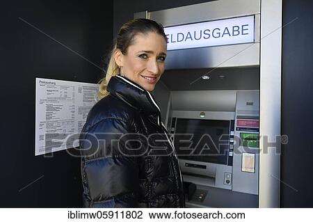 Stock Image - Woman standing in front of an ATM at a savings bank, Waiblingen, Baden-Württemberg, Germany, Europe. Fotosearch