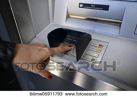 Stock Image - Woman typing in secret code at the cash machine of a savings bank, Waiblingen, Baden-Württemberg, Germany, Europe. Fotosearch