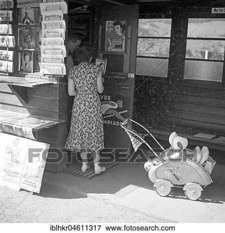 Stock Photo - Woman with pram looks after newspapers, newspaper shop, ca. 1955, Freiburg, Germany, Europe. Fotosearch