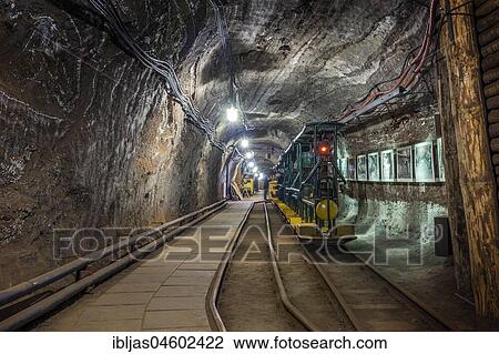 Stock Image - Yellow passenger underground train used in an old salt mine to transport tourists, Bochnia, Poland, Europe. Fotosearch
