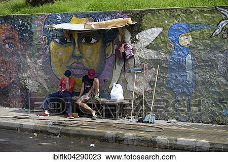 Stock Image - Young gang members sitting in front of graffiti wall, Comuna 8 slum, Medellin, Antioquia Department, Colombia, South America. Fotosearch