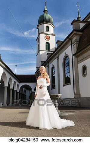 Young woman in white long wedding dress in front of church View Large Photo Image Stock Image - Young woman in white long wedding dress in front of church. Fotosearch