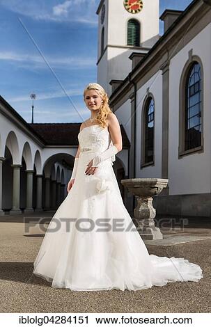 Young woman in white long wedding dress in front of church View Large Photo Image Stock Image - Young woman in white long wedding dress in front of church. Fotosearch