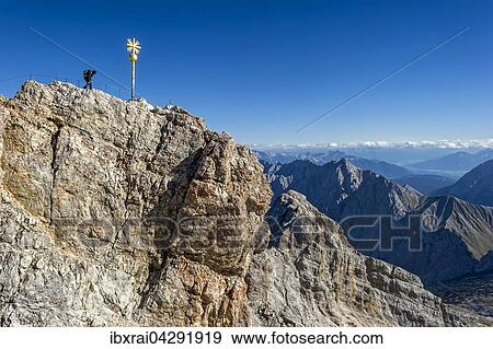 Bergsteiger am Gipfelkreuz der Zugspitze, Ausblick nach Tirol, Garmisch-Partenkirchen, Wettersteingebirge, Alpen, Oberbayern, Bayern, Deutschland, Europa View Large Photo Image Stock Photo - Bergsteiger am Gipfelkreuz der Zugspitze, Ausblick nach Tirol, Garmisch-Partenkirchen, Wettersteingebirge, Alpen, Oberbayern, Bayern, Deutschland, Europa. Fotosearch