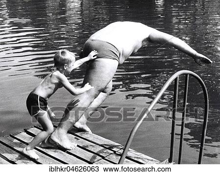 Stock Image - Boy throws man in the water ca. 1970s, exact place unknown, Czech Republic, Europe. Fotosearch