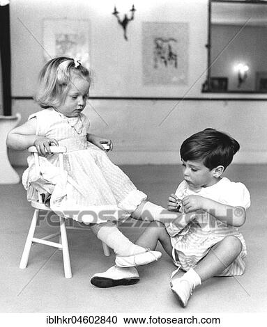 Stock Image - Boy ties up girls shoes, England, Great Britain. Fotosearch