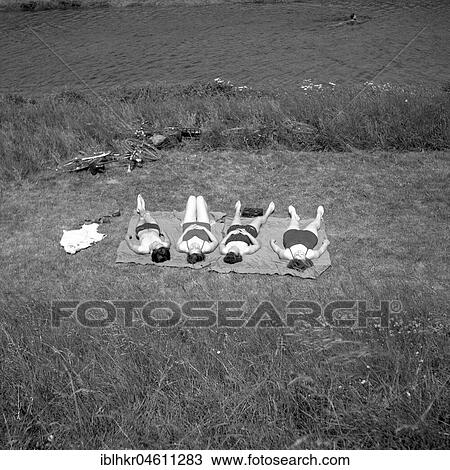 Four people lie on the shore and sunbathe, ca. 1950, near Freiburg, Germany, Europe View Large Photo Image Stock Image - Four people lie on the shore and sunbathe, ca. 1950, near Freiburg, Germany, Europe. Fotosearch