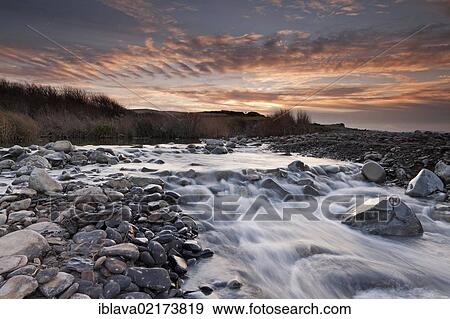 Looking towards the sun setting over the Quantock Hills and the cliffs of Kilve Beach, with Kilve Pill in the foreground, against a mackerel sky, Somerset, England, United Kingdom, Europe View Large Photo Image Stock Photo - Looking towards the sun setting over the Quantock Hills and the cliffs of Kilve Beach, with Kilve Pill in the foreground, against a mackerel sky, Somerset, England, United Kingdom, Europe. Fotosearch