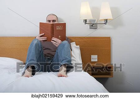 Stock Photo - Man, 30-40 years, reading Holy Bible in a hotel room. Fotosearch