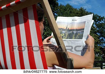 Stock Photography - Man in deck chair reading newspaper, Germany, Europe. Fotosearch