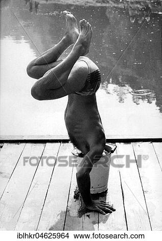 Man makes handstand and sticks head in bucket ca. 1970s, exact place unknown, Czech Republic, Europe View Large Photo Image Picture - Man makes handstand and sticks head in bucket ca. 1970s, exact place unknown, Czech Republic, Europe. Fotosearch