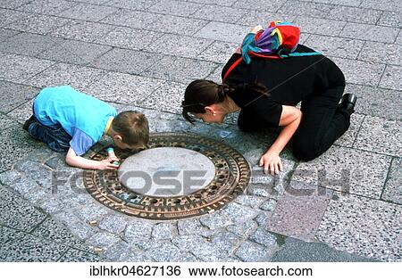 Mother and child looking in manhole cover, Berlin, Germany, Europe View Large Photo Image Stock Photograph - Mother and child looking in manhole cover, Berlin, Germany, Europe. Fotosearch