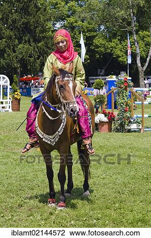Stock Image - Rider of the Royal Cavalry of Oman wearing a brightly-coloured uniform during a presentation at Pferd International Muenchen, the International Horse Show in Munich, Bavaria, Germany, Europe. Fotosearch