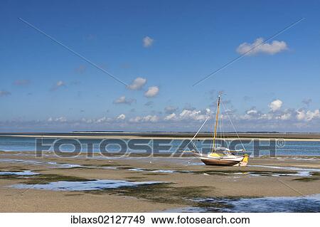 Stock Photo - Sailboat stranded at low tide near Wittduen facing Foehr, Amrum, North Friesland district, Schleswig-Holstein, Germany, Europe. Fotosearch