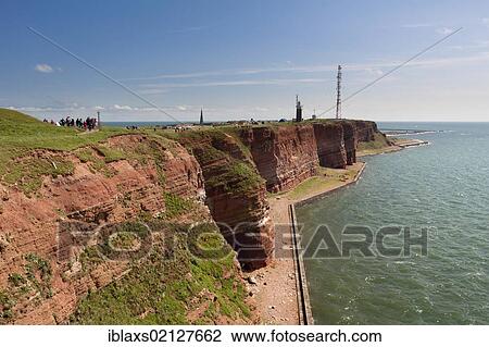 Stock Image - The prominent steep red sandstone cliffs of Heligoland with its lighthouse and a radio tower, Helgoland, Schleswig-Holstein, Germany, Europe. Fotosearch