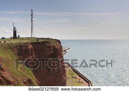 Stock Photo - The prominent steep red sandstone cliffs of Heligoland with its lighthouse and a radio tower, Helgoland, Schleswig-Holstein, Germany, Europe. Fotosearch
