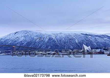Stock Photo - Tromsdalen from the harbour area of Tromsø, Tromso, during the winter twilight, with Tromsdalen Church, Arctic Cathedral or Ishavskatredalen, and Tromsø Bridge, Norway, Europe. Fotosearch