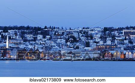 Stock Photo - View across the fjord from Tromsdalen, to the downtown harbour area of Tromsø, Tromso, with the Rica Ishavshotel, the Hotel With and the Norges Raisklag, at dusk, Norway, Europe. Fotosearch