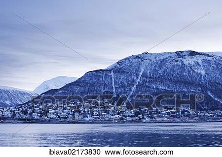 Stock Image - View of Storsteinen and Tromsdalen below, in the winter twilight, from the harbour area of Tromsø, Tromso, Norway, Europe. Fotosearch