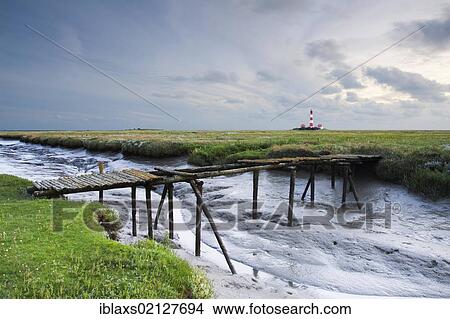 Picture - Westerhever lighthouse with a dilapidated bridge over a tidal gully, evening, Westerheversand, North Friesland district, Schleswig-Holstein, Germany, Europe. Fotosearch
