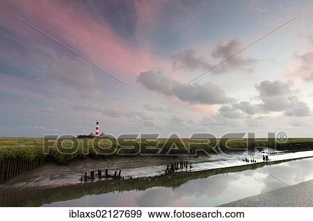 Stock Photo - Westerhever lighthouse with a tidal gully at front shortly after sunset, Westerheversand, North Friesland district, Schleswig-Holstein, Germany, Europe. Fotosearch