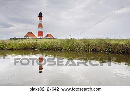 Stock Image - Westerheversand Lighthouse on the Eiderstedt Peninsula, with a reflection, North Frisia, Schleswig-Holstein, Germany, Europe. Fotosearch