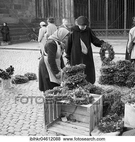 Woman inspects the goods at a market stall with Christmas wreaths, Freiburger Münstermarkt, approx. 1945 to 1955, Freiburg, Germany, Europe View Large Photo Image Stock Photo - Woman inspects the goods at a market stall with Christmas wreaths, Freiburger Münstermarkt, approx. 1945 to 1955, Freiburg, Germany, Europe. Fotosearch