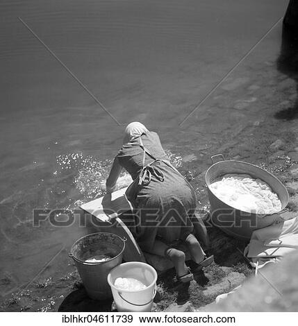 Stock Photo - Woman washes her clothes in an old-fashioned way in the river around 1950, Freiburg, Germany, Europe. Fotosearch