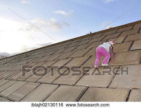 Stock Photograph - Young girl, 5 years, climbing up a steep concrete slope. Fotosearch