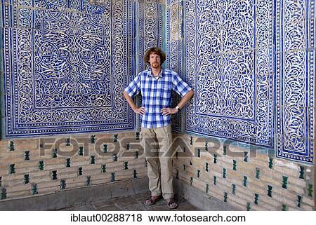 Stock Photo - Young man at fine decorated wall with blue and white glazed tiles and zoroastrian symbols of ease Tash Hauli Palace Khiva Uzbekistan. Fotosearch