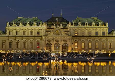 Stock Photo - Christmas lights with Christmas Market in front of Belvedere Palace, reflection in the lake, Vienna, Austria, Europe. Fotosearch
