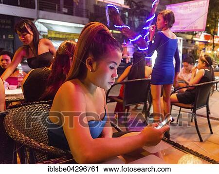 Stock Image - Nightlife, barmaid holding smartphone, clubs, Phnom Penh, Cambodia, Asia. Fotosearch