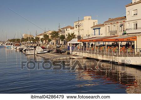 Promenade with restaurants and fishing boats at the harbor, Petit Camargue, Le-Grau-du-Roi, Department Gard, Languedoc-Roussillon, France, Europe View Large Photo Image Stock Photo - Promenade with restaurants and fishing boats at the harbor, Petit Camargue, Le-Grau-du-Roi, Department Gard, Languedoc-Roussillon, France, Europe. Fotosearch
