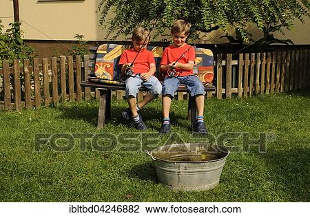 Twins sitting side by side on bench in garden, fishing in bathtub View Large Photo Image Stock Image - Twins sitting side by side on bench in garden, fishing in bathtub. Fotosearch