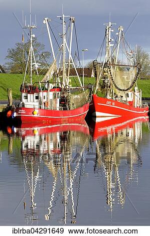 Stock Photo - Two red shrimp boats in Greetsiel harbour basin, North Sea, Lower Saxony, Germany, Europe. Fotosearch