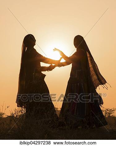 Two women in dresses dancing in front of the setting sun, Pushkar Camel Fair, Pushkar, Rajasthan, India, Asia View Large Photo Image Stock Photo - Two women in dresses dancing in front of the setting sun, Pushkar Camel Fair, Pushkar, Rajasthan, India, Asia. Fotosearch