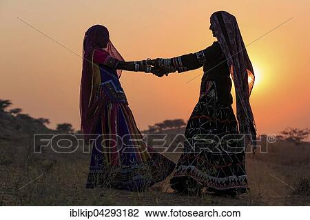 Two young women in dresses dancing in front of the setting sun, Pushkar Camel Fair, Pushkar, Rajasthan, India, Asia View Large Photo Image Stock Image - Two young women in dresses dancing in front of the setting sun, Pushkar Camel Fair, Pushkar, Rajasthan, India, Asia. Fotosearch