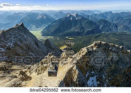 Stock Image - Tyrolean Zugspitzbahn gondola, view from Zugspitze, Mount Daniel of Ammergau Alps in Tyrol, left Zugspitzeck, Wetterstein, Garmisch-Partenkirchen, Upper Bavaria, Bavaria, Germany, Europe. Fotosearch