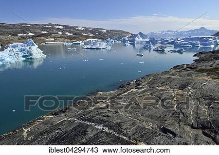 Stock Image - Woman on the shore of Tasiilaartik Fjord, Kalaallit Nunaat, Greenland, North America. Fotosearch