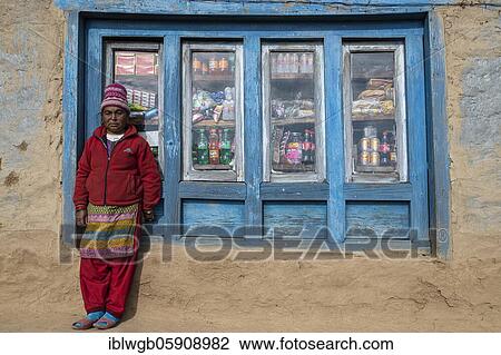 Stock Image - A local woman is standing in front of the window of her shop, Himalaya, Solu Khumbu, Everest region, Nepal, Asia. Fotosearch