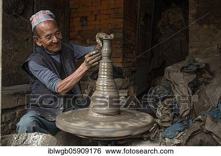 Stock Photograph - A potter working at his potter's pane, pottery market, Bhaktapur, Kathmandu valley, Nepal, Asia. Fotosearch