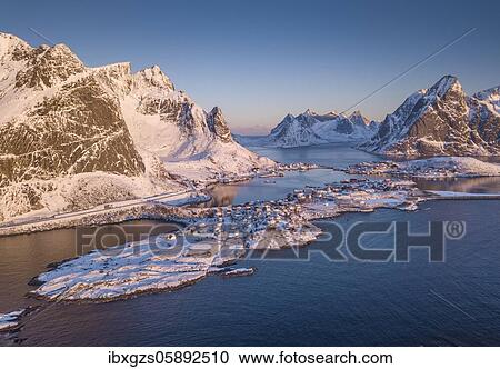 Stock Image - Aerial view, fjord landscape at sunrise, snowy mountains in winter, fishing village Reine, Nordland, Lofoten, Norway, Europe. Fotosearch