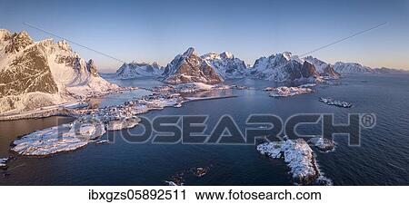 Stock Image - Aerial view, fjord landscape at sunrise, snowy mountains in winter, fishing village Reine, Nordland, Lofoten, Norway, Europe. Fotosearch