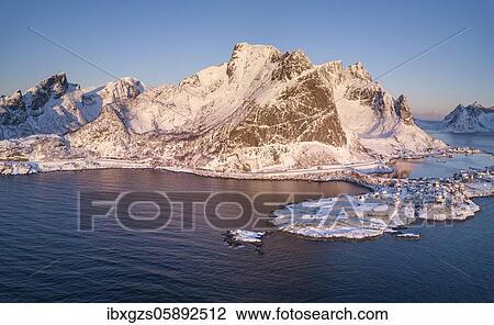 Stock Image - Aerial view, fjord landscape at sunrise, snowy mountains in winter, fishing village Reine, Reine, Nordland, Lofoten, Norway, Europe. Fotosearch