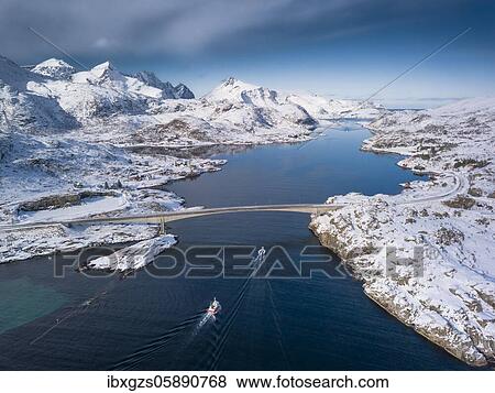 Stock Photo - Aerial view, Fjord seaway with snowy mountains, bridge with road and small fishing boats, Nordland, Lofoten, Norway, Europe. Fotosearch