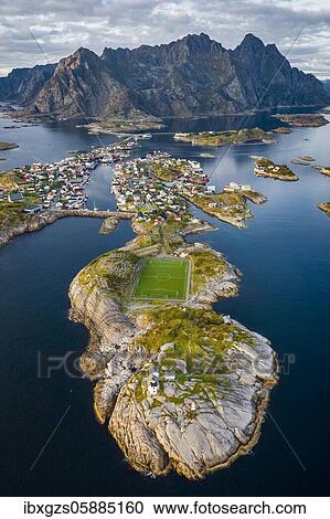 Stock Image - Aerial view of the island world near the fishing village Henningsvaer, in front peninsula with football field, in the back mountain range Vagakallen with summits Festvagtinden, Budalsdinten and Kvanndalstinden, Vågan, Lofoten, Nordland, Norway, Europe. Fotosearch