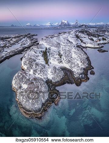 Picture - Aerial view of winter island landscape in the evening light off the coast, high mountain peaks in the background, Dønna, Nordland, Norway, Europe. Fotosearch