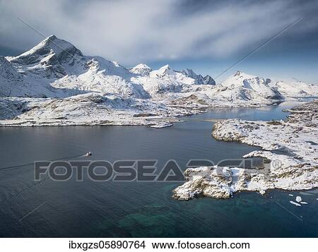 Picture - Aerial view, turquoise fjord with snowy mountains, road bridge and small fishing boat, Nordland, Lofoten, Norway, Europe. Fotosearch