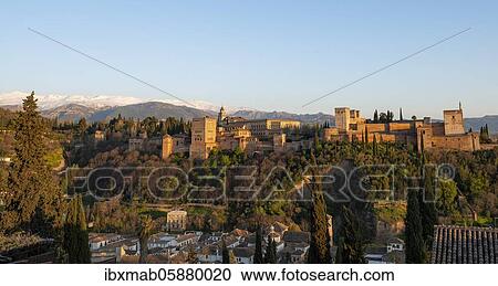 Stock Image - Alhambra on the Sabikah hill at sunset, Moorish citadel, Nasrid palaces, Palace of Charles the Fifth, behind Sierra Nevada with snow, Granada, Andalucia, Spain, Europe. Fotosearch